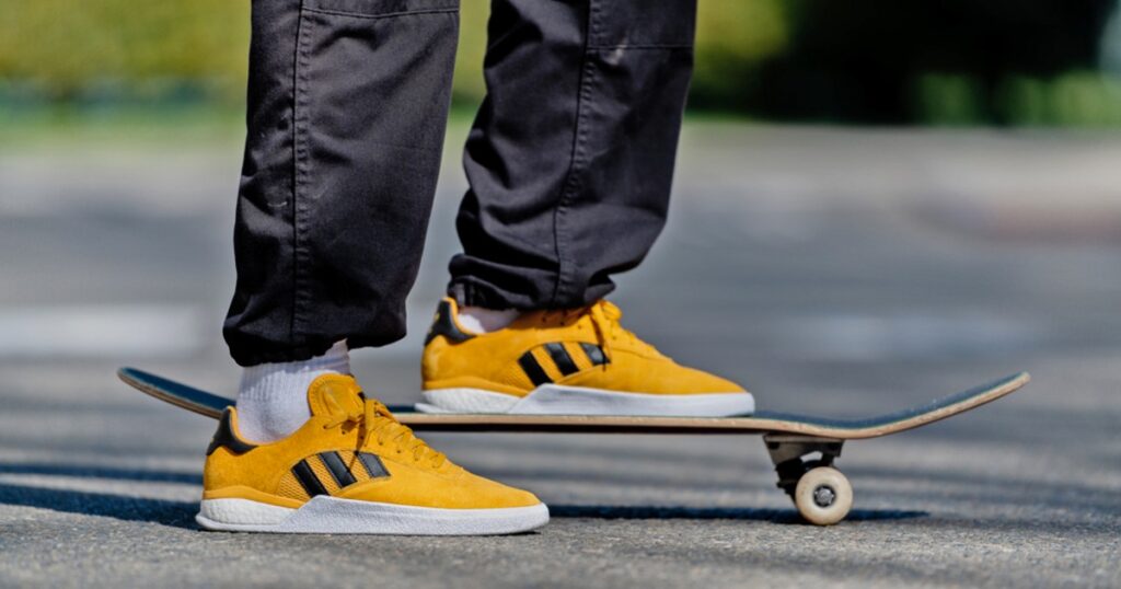 man standing on skateboard with yellow adidas